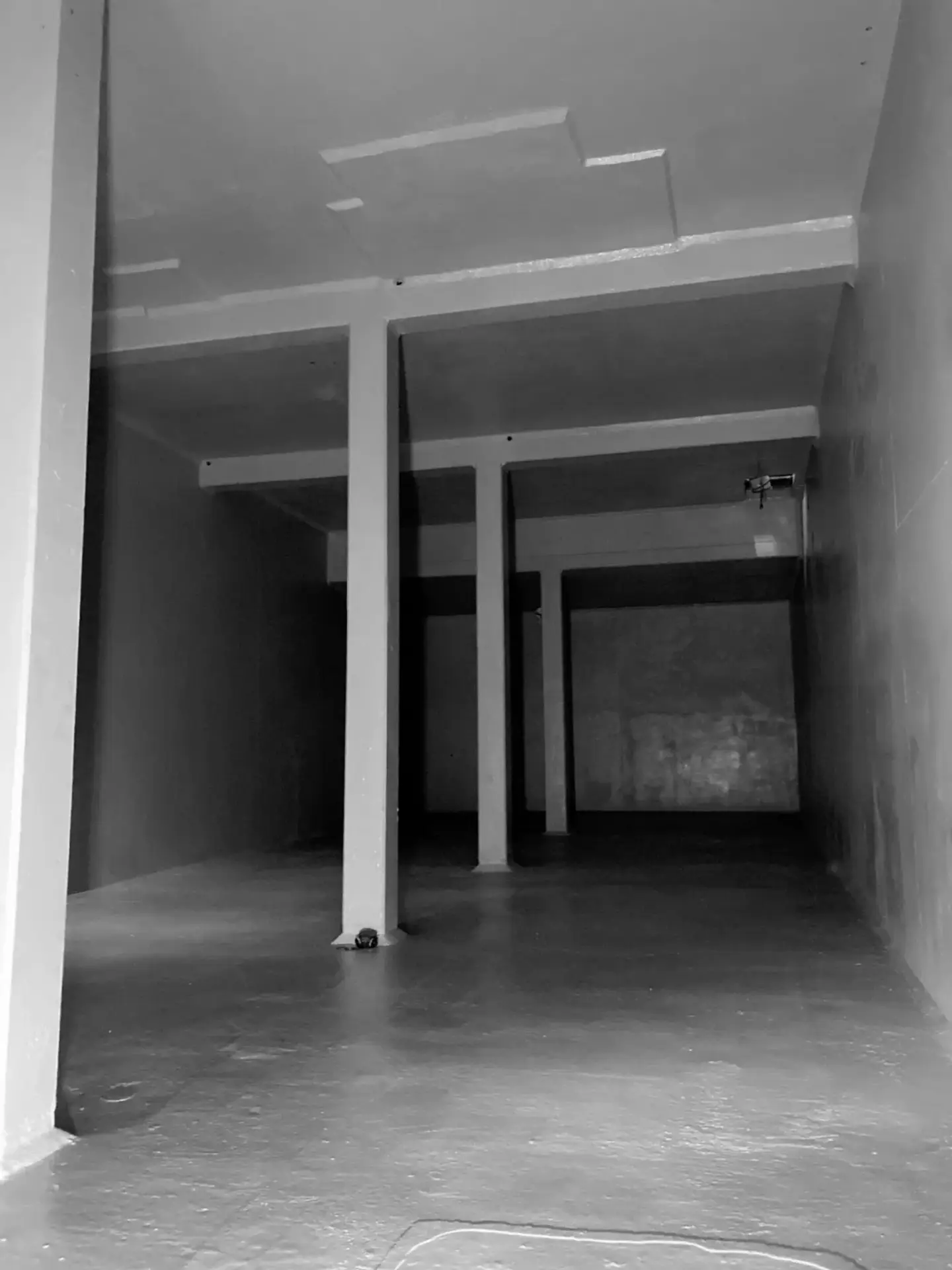 Betonnen ruimte met meerdere steunpilaren, wanden en plafond die volledig zijn afgewerkt met een uniforme beschermcoating, zichtbaar na renovatiewerken.