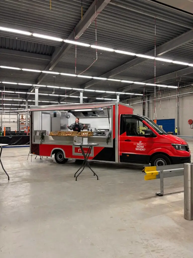 Rode Renotec-foodtruck met open zijwand en cateringopstelling, opgesteld in een ruime industriële hal.