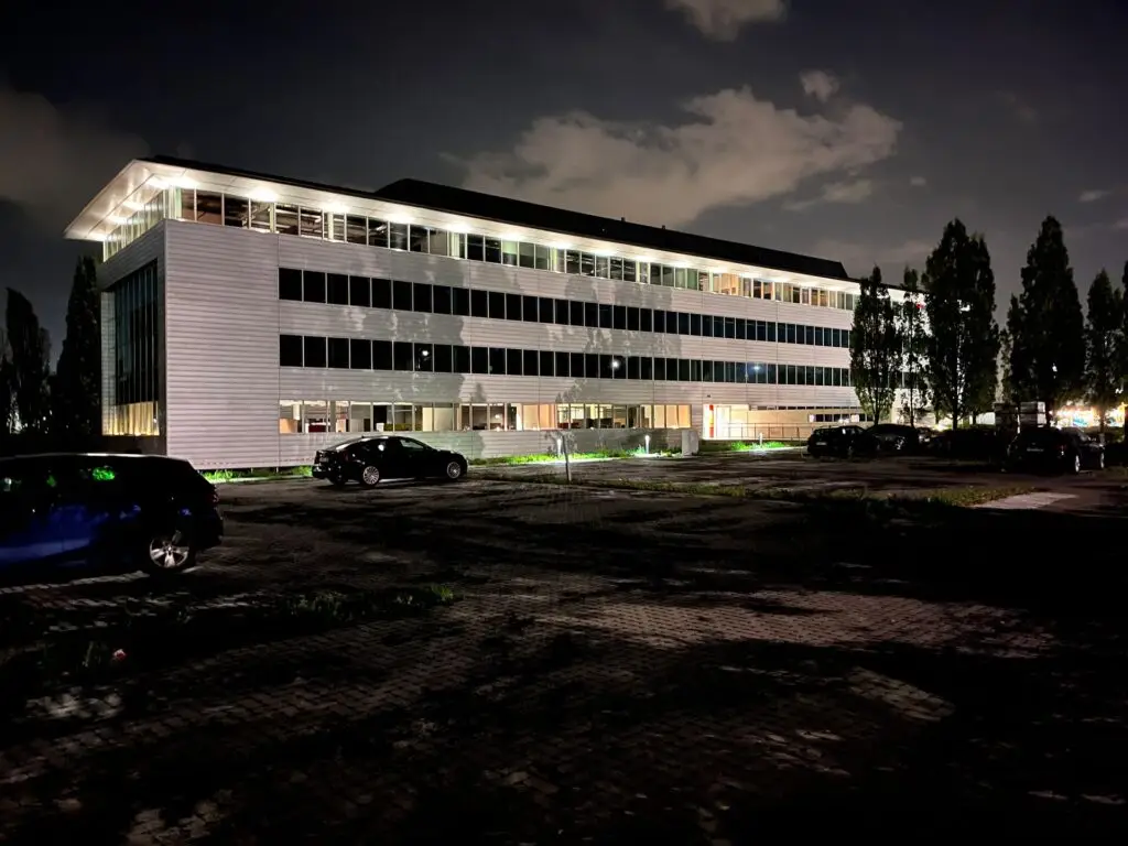 Exterieur van het Renotec‑kantoor in Brussel bij avond, met moderne gevel en verlichte kantoorruimte.