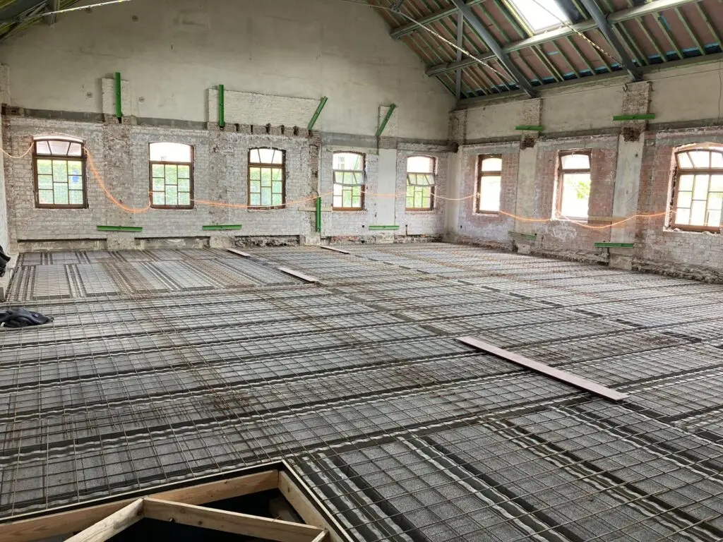 Voorbereidende vloeropbouw met wapening tijdens renovatie‑ en stabilisatiewerken door Renotec in bestaand gebouw.