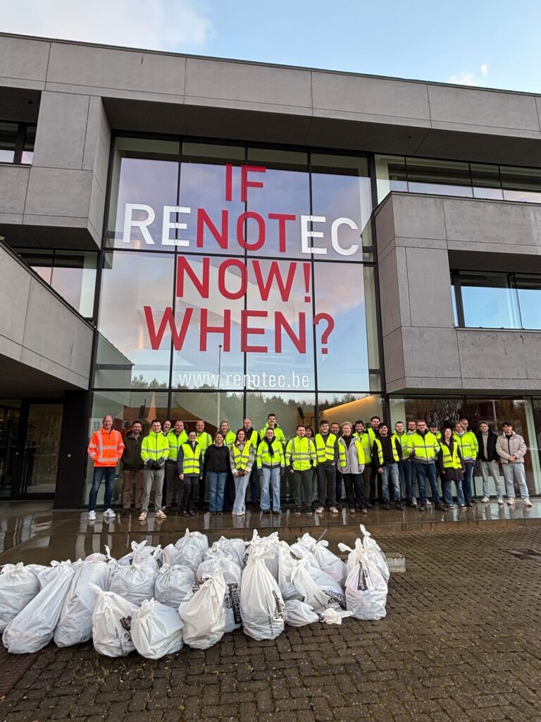 Groep Renotec-medewerkers in fluohesjes met ingezamelde vuilniszakken voor bedrijfsgebouw, resultaat van zwerfvuilactie en inzet voor omgeving en duurzaamheid