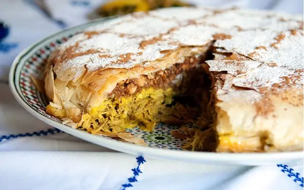 Traditionele Marokkaanse bastilla met kip en specerijen, geserveerd op kleurrijk bord